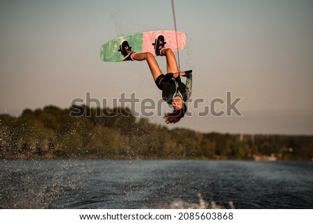 Beautiful view of active female rider holding rope and making extreme jump on wakeboard. Wakeboarding and water sports activity. Stock fotó © 