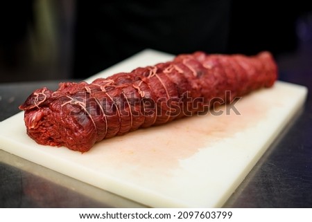 beautiful view on appetizing raw meatloaf tied with threads on a white cutting board. Meat dishes Foto stock © 
