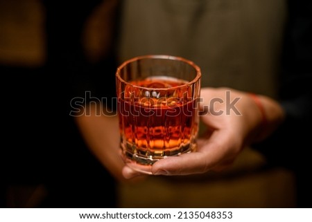 selective focus of old-fashioned glass with cold alcoholic drink and a piece of ice in male hand 商業照片 © 