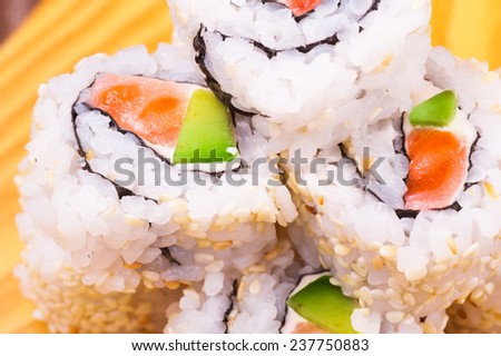 inside out sushi roll with salmon and avocado on wooden background