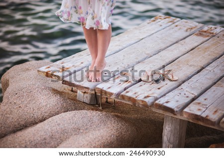barefoot girl on wooden bridge above water no face