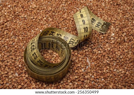 yellow centimeter tape on buckwheat background texture