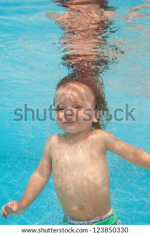 Happy toddler kid diving under water in the pool