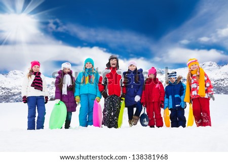 Row of large group of kids, friends, boys and girls standing together outside in snow