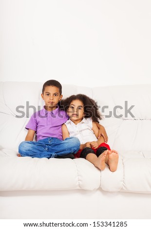 Brother and sister siblings sitting on the couch at home interior