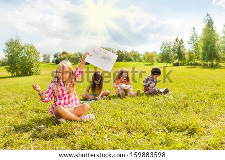 Little blond girl showing off her painting with her friends drawing on background
