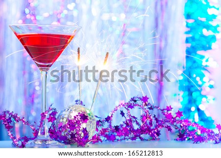Cocktail glass with alcohol cocktails with festive Christmas decoration and burning sparklers with sparks
