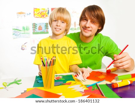 Happy dad parenting with little happy son teaching him to make crafts out of paper