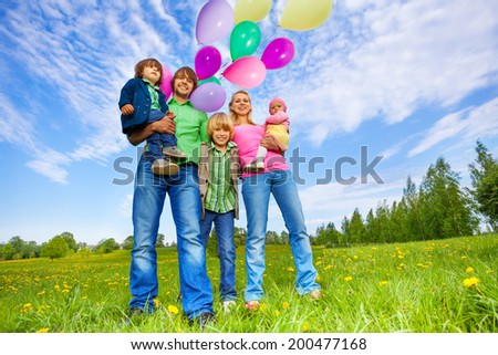 Happy family stands with balloons in park