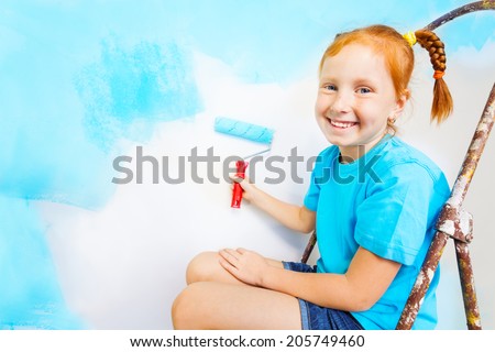 Little girl in blue shirt sits on a ladder