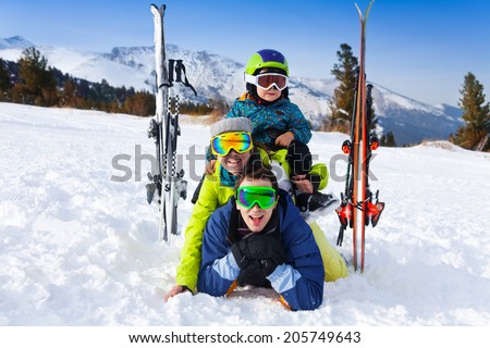Family in ski masks laying and kid on shoulders