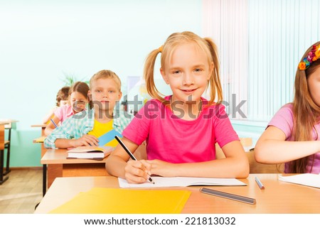 Kids sitting at table in classroom and writing