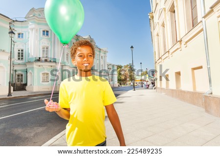 Happy African boy in yellow T-shirt with  balloon