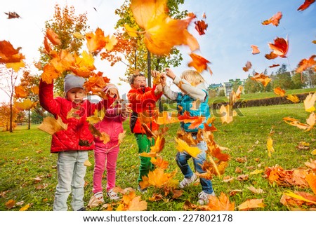 Active group of children play with flying leaves