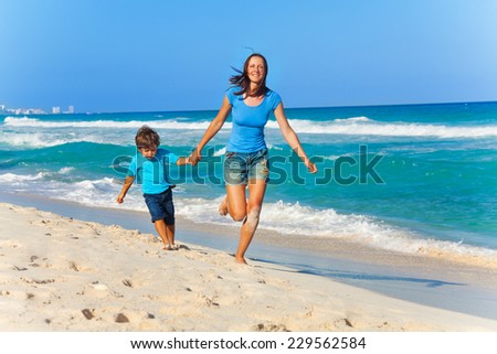 Smiling mother and son hold arms while running