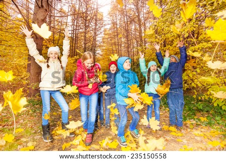 Excited kids play together with flying leaves