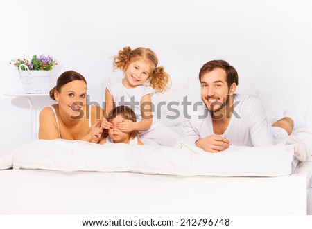Happy family laying on white bed in pajamas