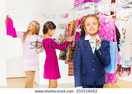 One boy with shopping bag and girls choose clothes