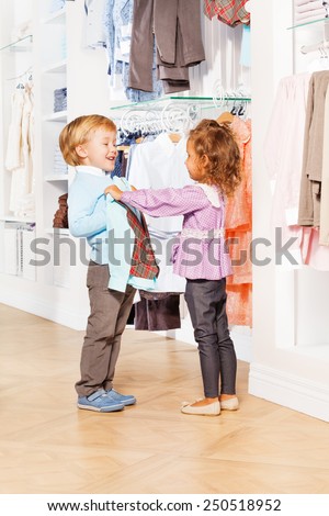 Laughing cute boy and girl choose clothes together