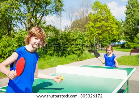 Boy with racket serves table tennis ball to girl