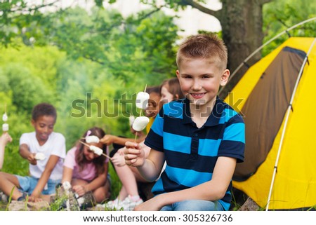 Boy holding stick with marshmallows during camping
