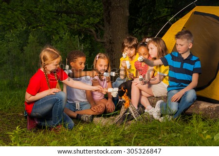 Diverse kids with marshmallow treat near bonfire