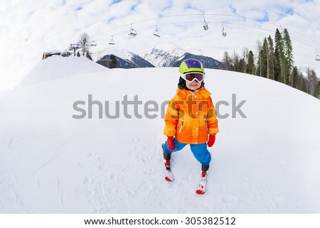 Small boy in ski mask and helmet skiing alone on Sochi ski resort Krasnaya polyana in Russia