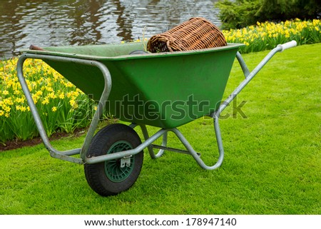 Wheelbarrel containing gardening tools standing on freshly mown lawn