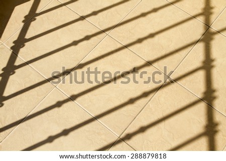 The shadow of the balcony railing in sunlight stripes on a stone slab