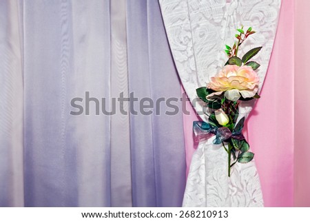 Part of beautifully draped curtain with patterns and a flower