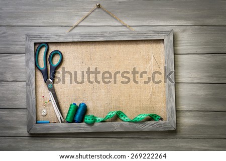 Frame on wooden background and items for sewing.