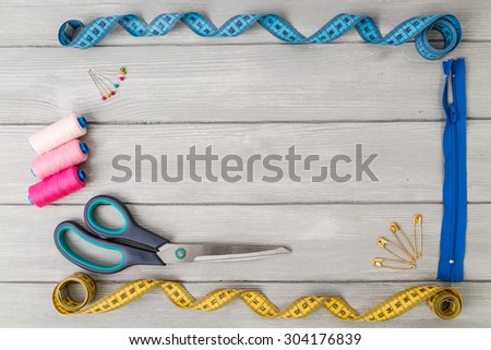 Frame on wooden background and items for sewing.