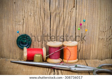Vintage background with sewing tools and sewing kit. Scissors, bobbins, buttons on the old wooden background.