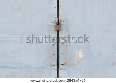 steel door of warehouse is lock with small key.it is old and rusty