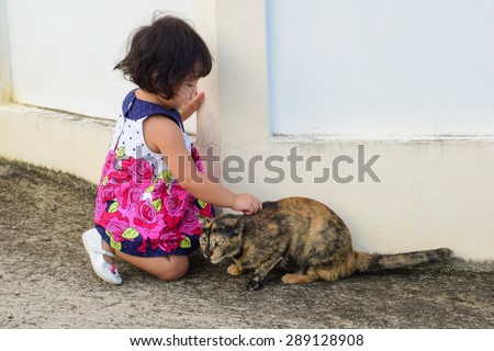 baby girl playing with stray cat  side house wall.it danger but she can control cat and easy