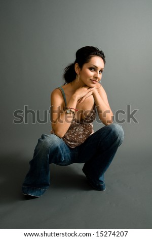 a young attractive hispanic female crouches down for a pose