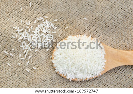 Raw rice on wooden ladle with sack background