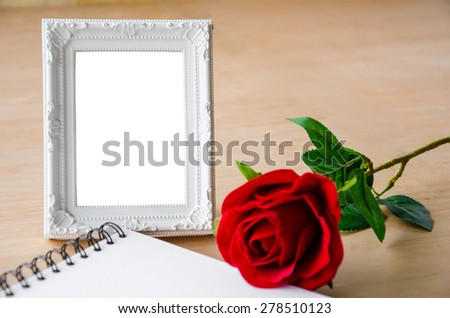 Close up Blank white photo frame and red roses on wooden background, clipping path.