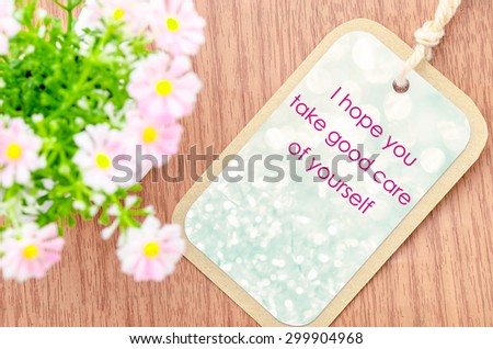 Take care of yourself greeting card with pink flower on wooden background.