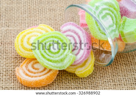 Sweet sugar candies in glass bottle on sack background.
