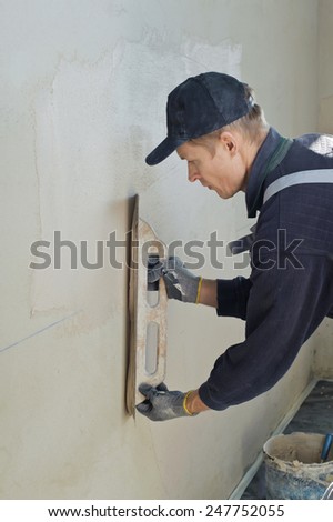 Man gets manually gypsum plaster on the wall