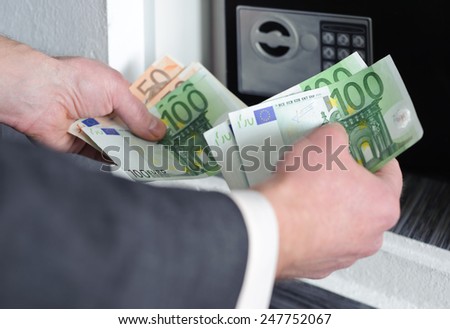 Human hands holding money against a background of safe