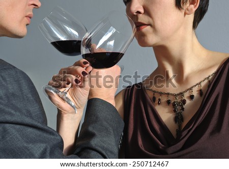 Man and woman drinking wine from goblets with his arms crossed