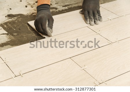 Laying Ceramic Tiles. Workers hand sets, plastic crosses between the tiles