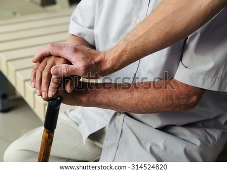 Hand of man touching hands elderly man with the walking stick