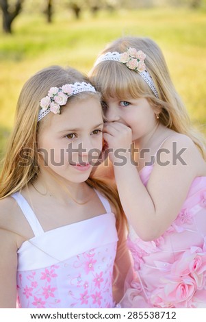 Two little cute girls sisters in pink dresses