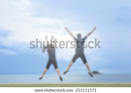 blurry photo of couple jumping  on the beach with sunset view behind