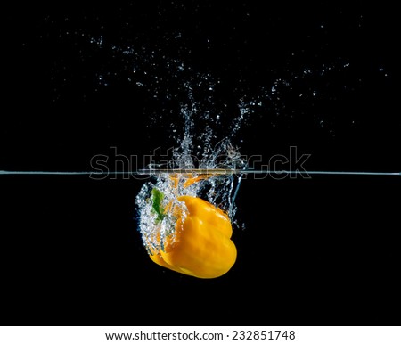 yellow pepper falling and splashing into water.