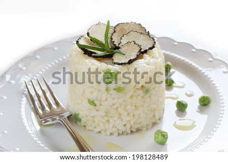Italian risotto with black truffle and green peas on white plate