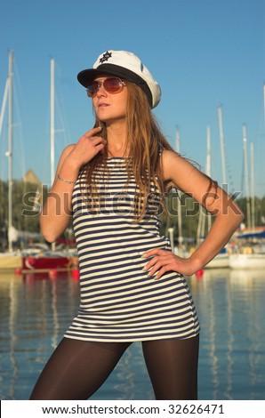 Sexy woman in sailor uniform posing in front of yachts